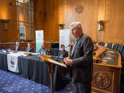 Senator Sheldon Whitehouse speaks in front of a podium at a hearing.
