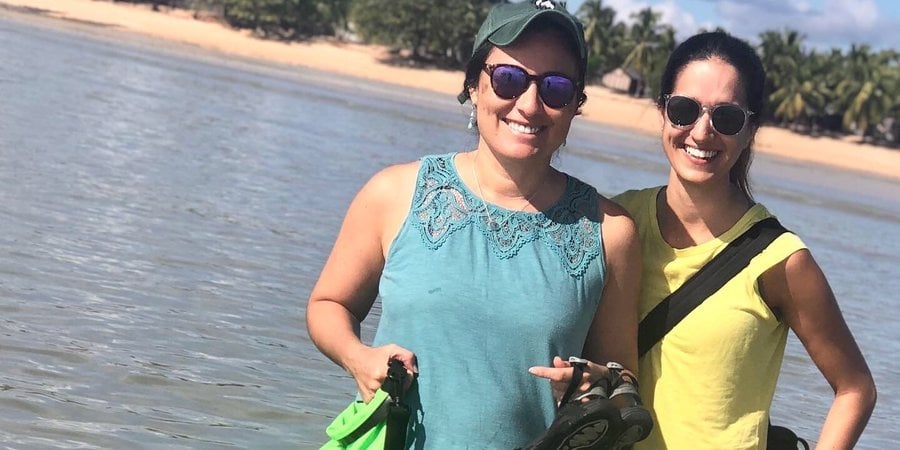 Shauna and Gabby smile at the camera with their arms around one another in front of the ocean in Madagascar