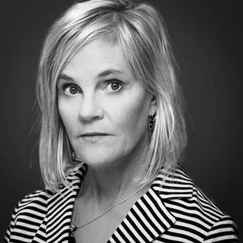 A black and white headshot of Sheila, who is a white woman with shoulder length blond hair.