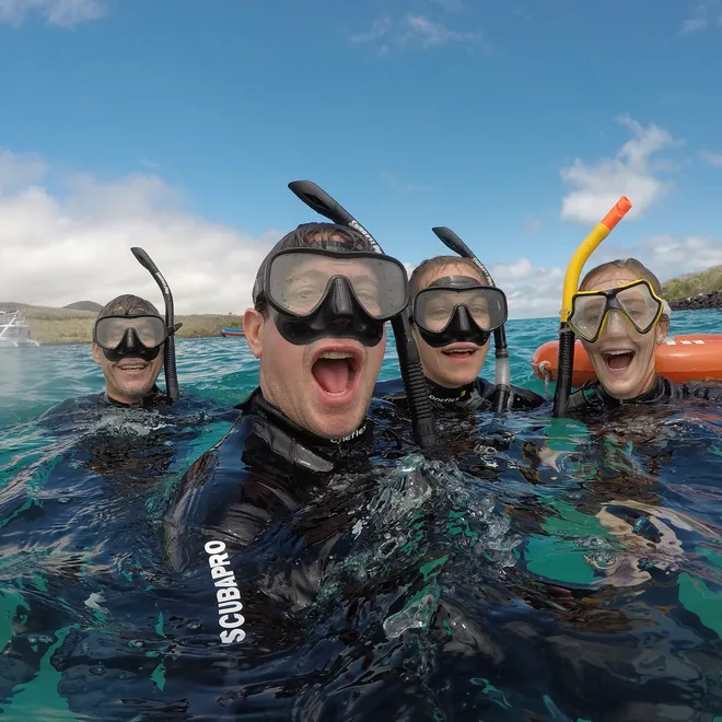 Four people with masks and snorkels floating in water