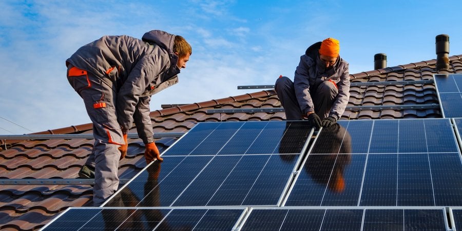 two people installing solar panels on a roof