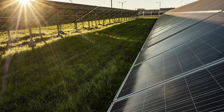 Solar panels stretch across a field as the sun sets