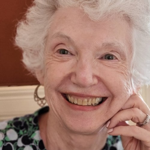 Susan Cook Hoganson smiles at the camera and rests her head gently on her hand.