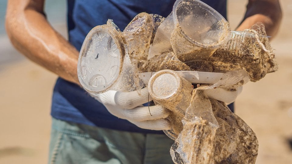 Man holding cups pulled out of sand