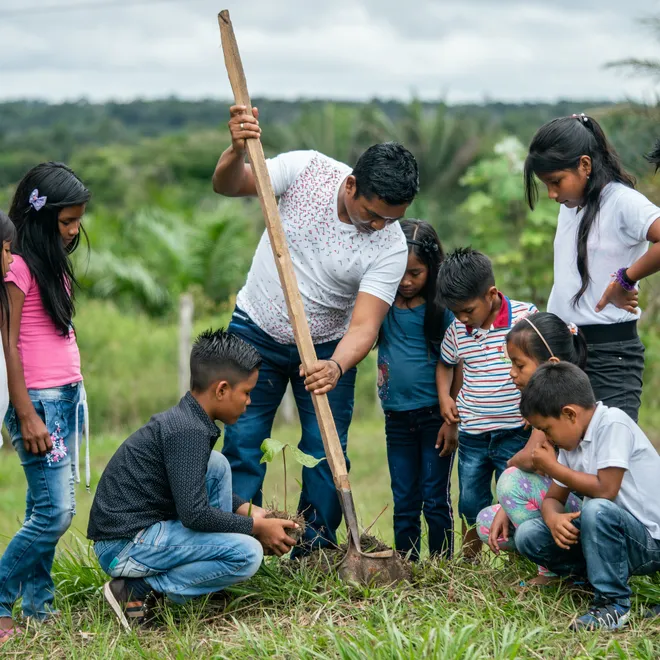 School teacher during a practical lesson outside of the classroom, planting trees in the school grounds