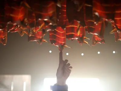 A finger reaches up to touch the oil dripping off a salmon smoking