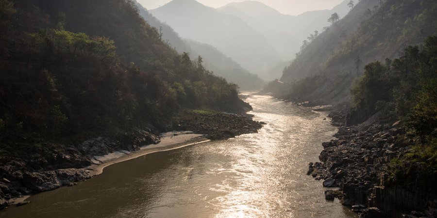View of a river from ground level in a deep valley surrounded by mountains