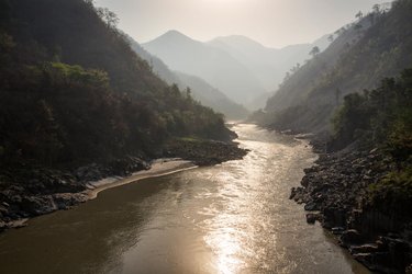View of a river from ground level in a deep valley surrounded by mountains