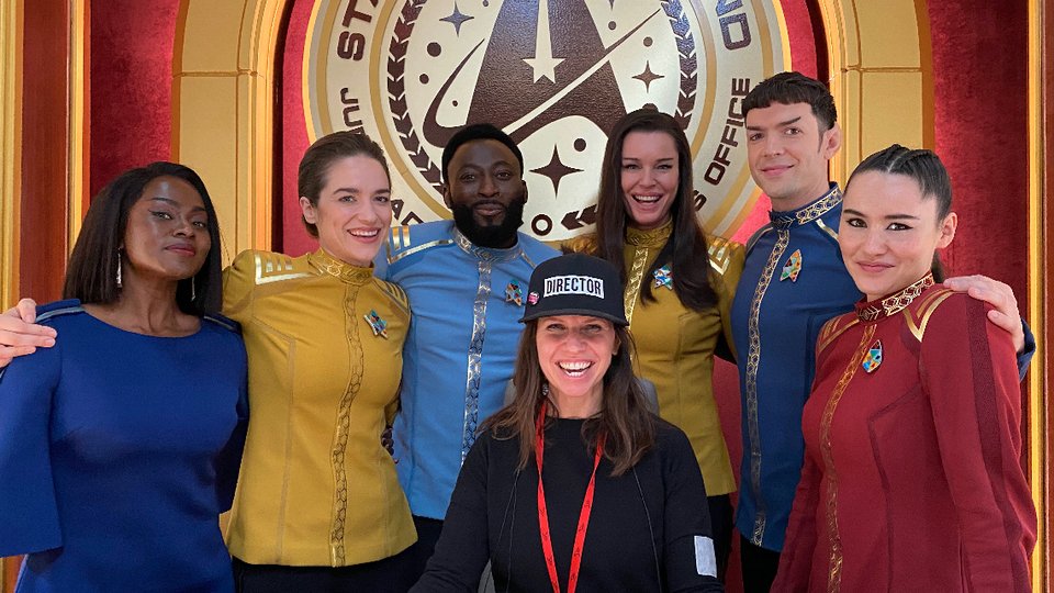 Valerie Weiss surrounded by actors in costume in front of "Starfleet Command" sign