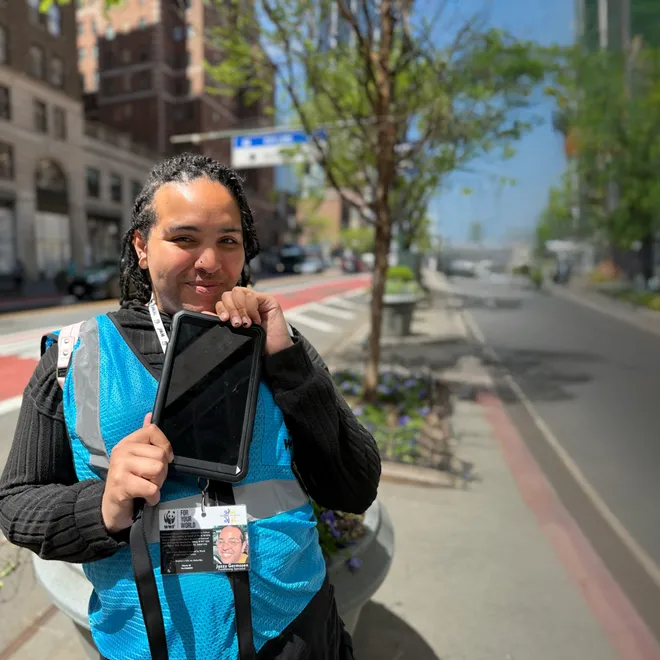 A woman in a WWF lanyard stands on a sidewalk and holds a tablet