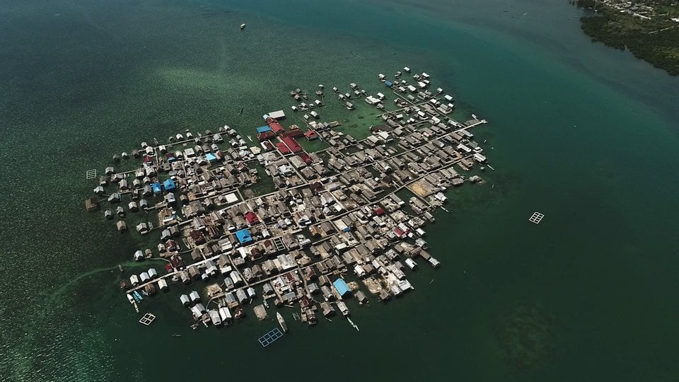 Aerial view of an island village cluster of houses built on stilts and docks out in the water