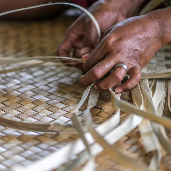 Closeup of hands weaving dry grass mats