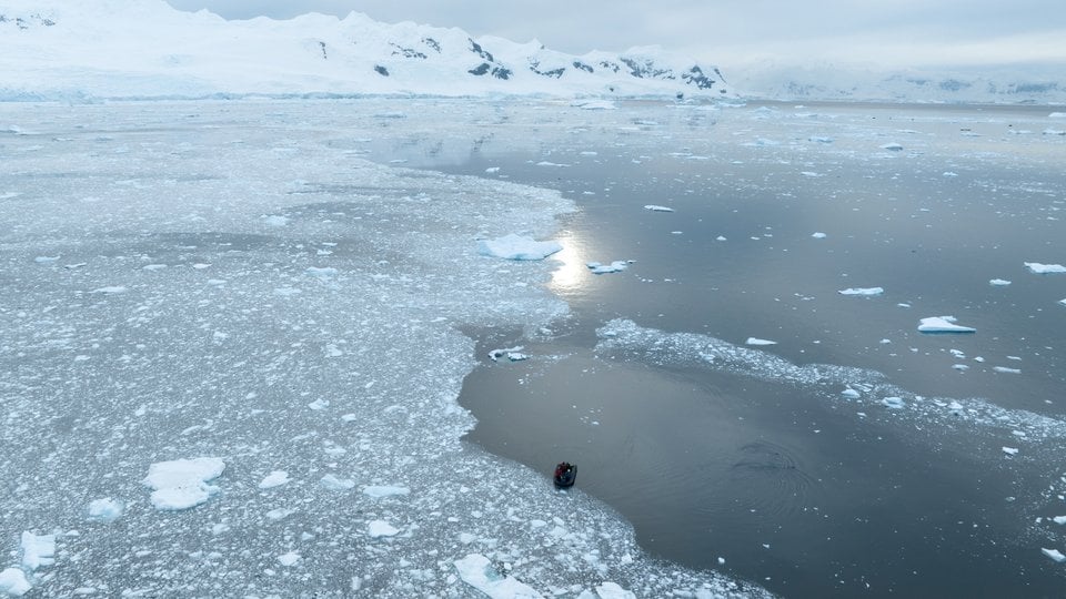 Aerial photo of small boat on water with sea ice