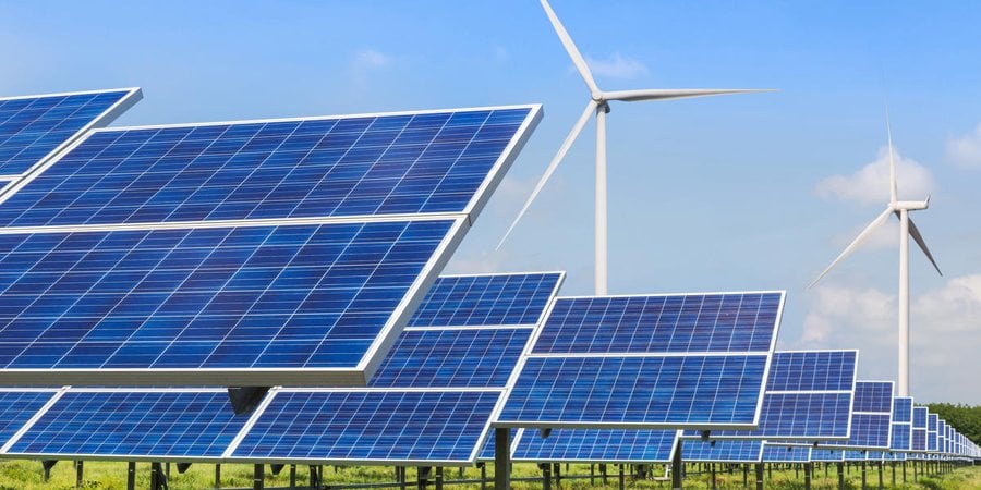 Solar panels in front of several wind turbines on a sunny day