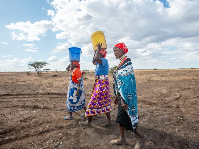 Women walking in a field with buckets on heads