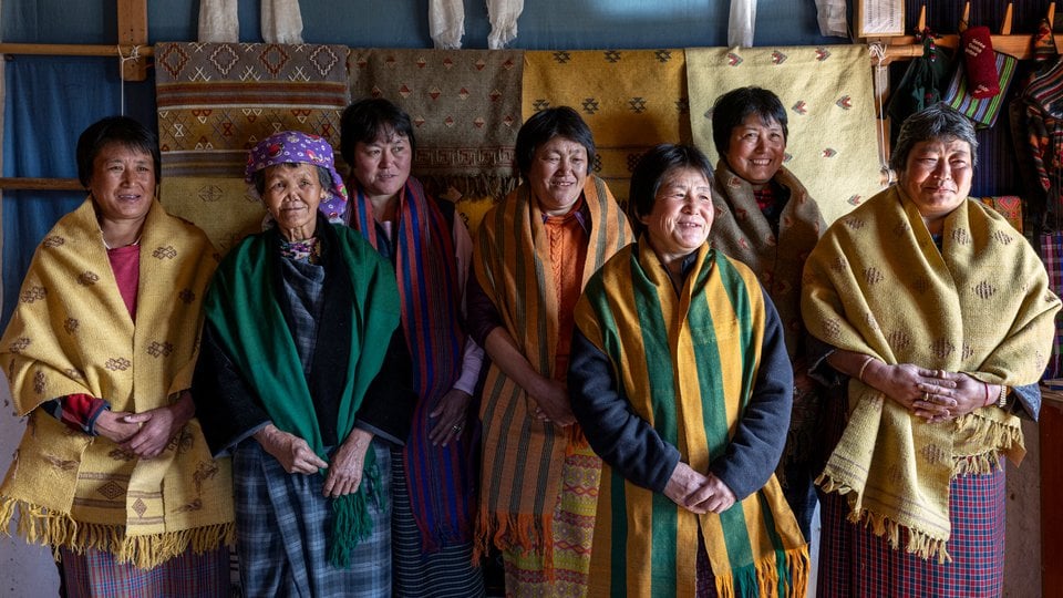 A group of smiling women wearing colorful woven cloth