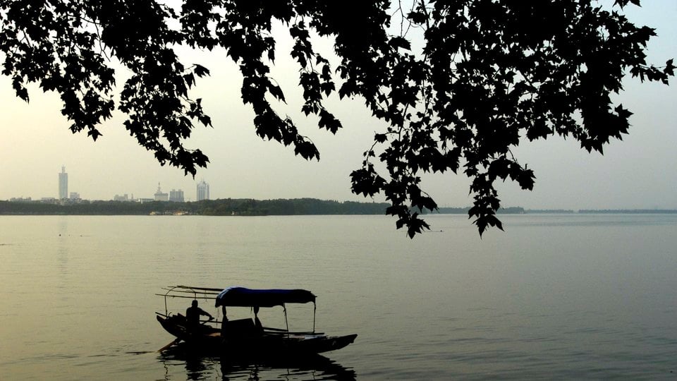 A waterway with a silhouette of a boat and a city in the background.