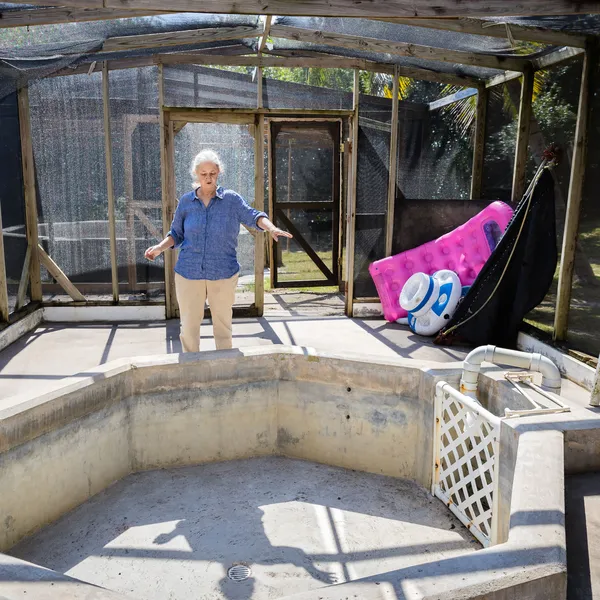Zoe Walker stands behind a concrete rehabilitation pool that is currently empty.