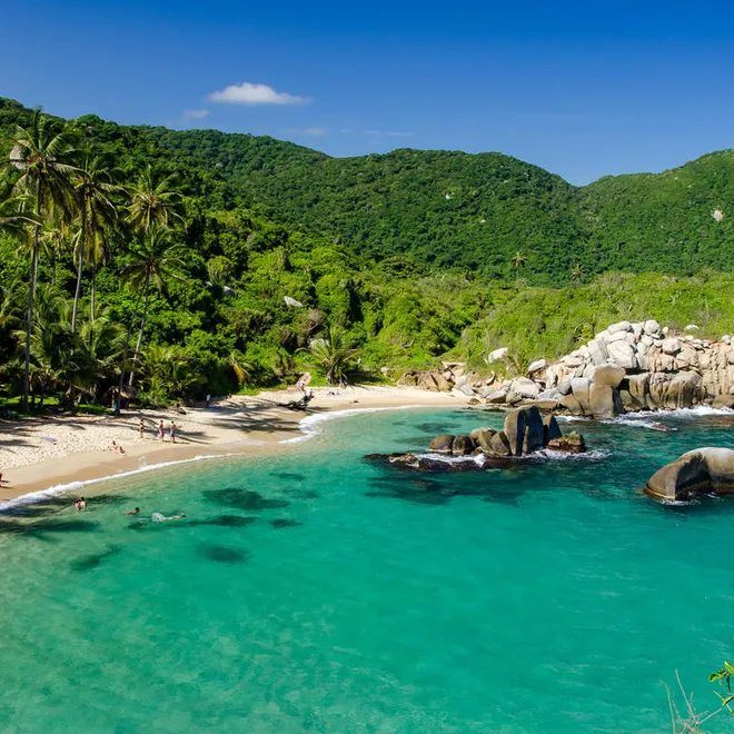 tropical beach with snorkelers and rock formations