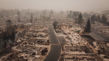Aerial view of a neighborhood scorched by wildfire with only foundations left of houses