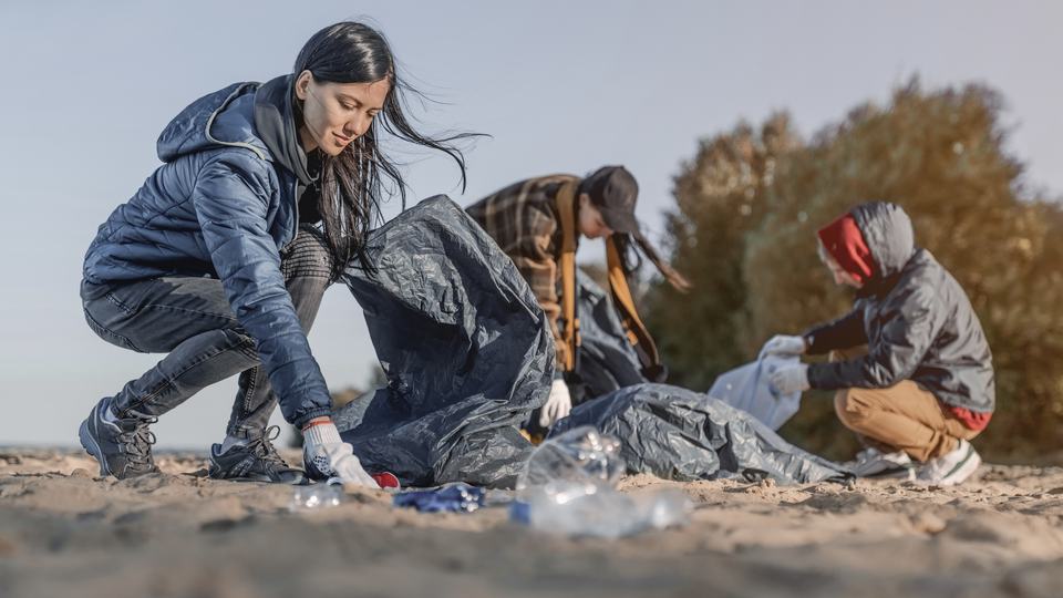 a group of people picking up trash on a beach