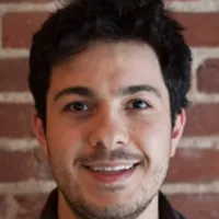 Headshot of Carlos Quintela set against brick wall in background