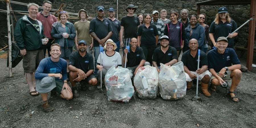 A group of people posing for the camera with bags of trash they've collected
