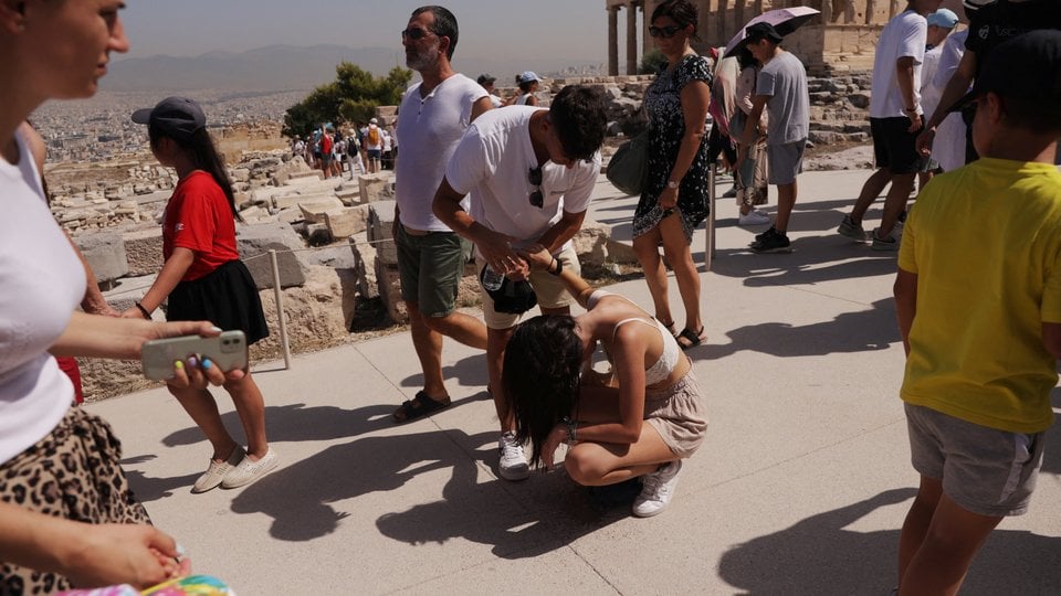 an tourist bends takes a break and kneels over in the extreme heat