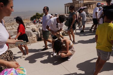 an tourist bends takes a break and kneels over in the extreme heat