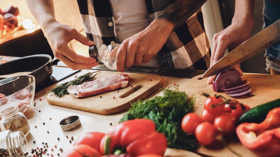 A photo showing meats and vegetables being prepared on a counter.