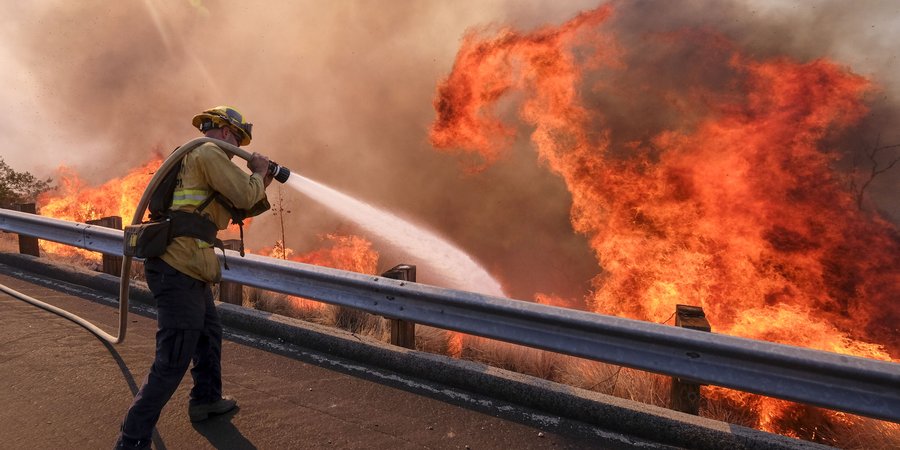 A firefighter battles wildfire near a freeway in Simi Valley, California