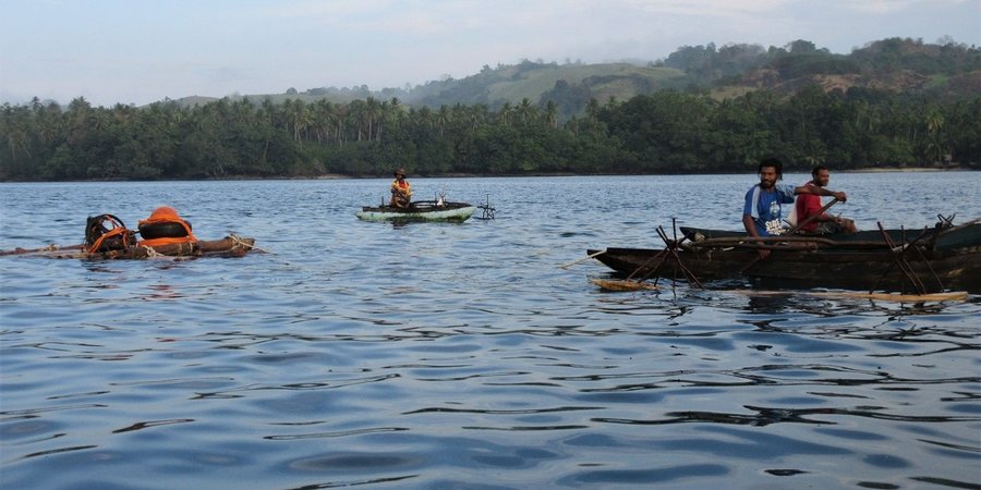 Community members row small boats on the coast of Papua New Guinea