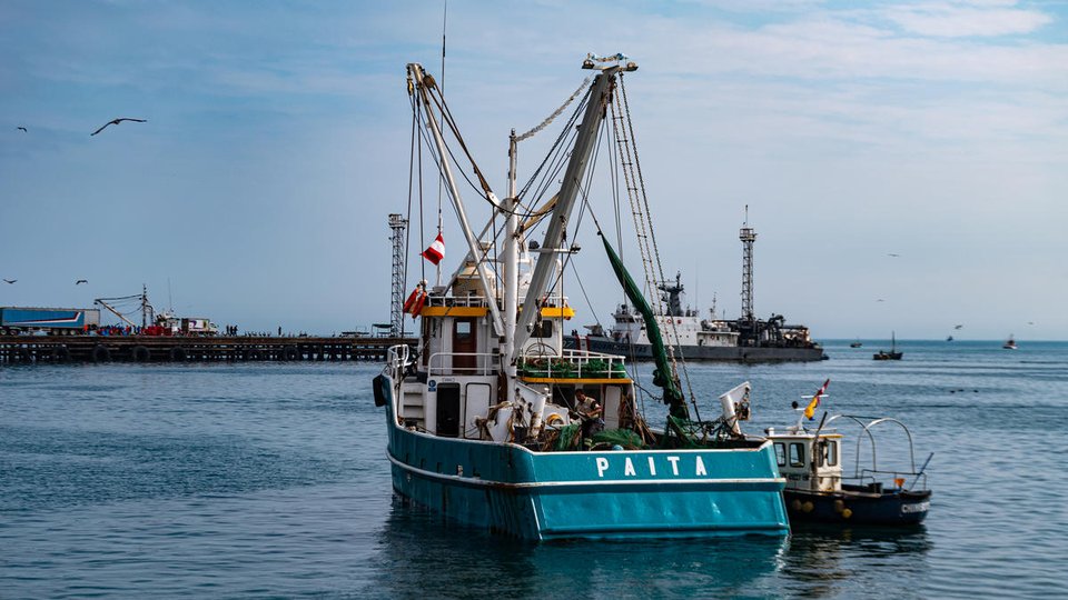 The rear view of a large blue industrial fishing boat on the water