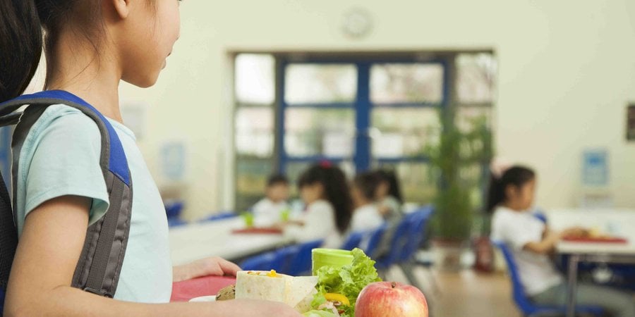 School girl holding food tray in school cafeteria