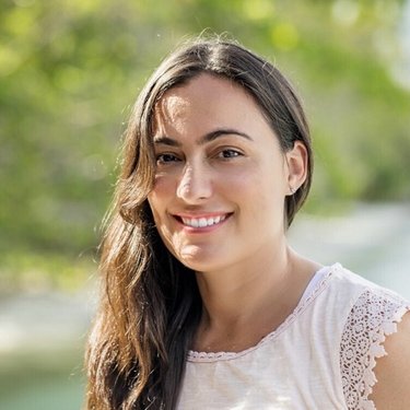 WWF's Gabby Ahmadia has long brown hair and wears a white shirt and smiles at the camera