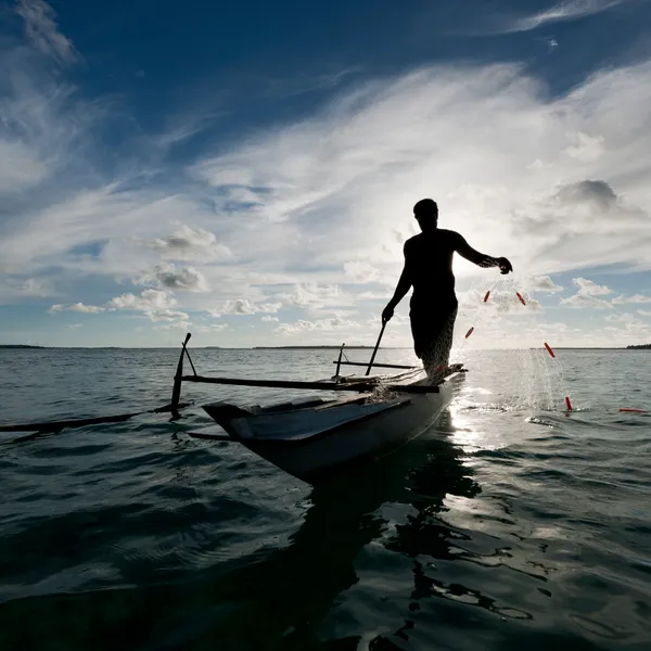 Person fishing with a net on a small boat