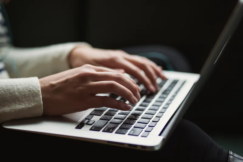 Close up of a person's hands typing on a laptop keyboard.