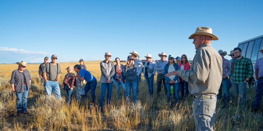 A group of younger ranchers listens to a more experienced rancher