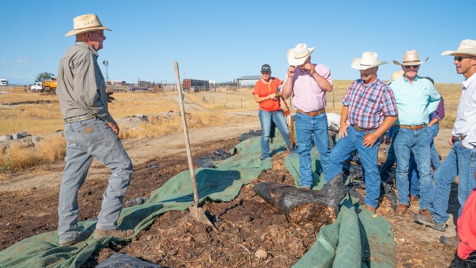 A rancher speaks to a group of others in a field