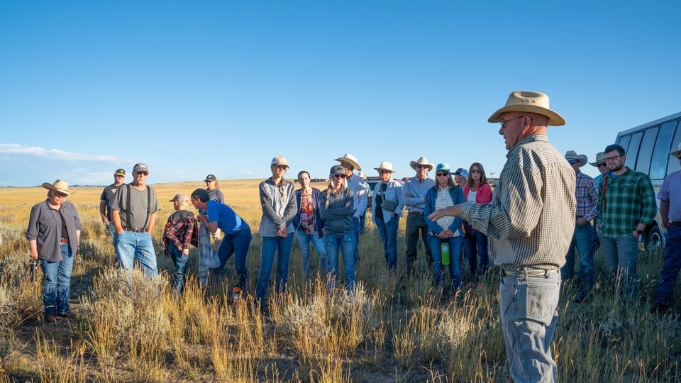 A group of younger ranchers listens to a more experienced rancher