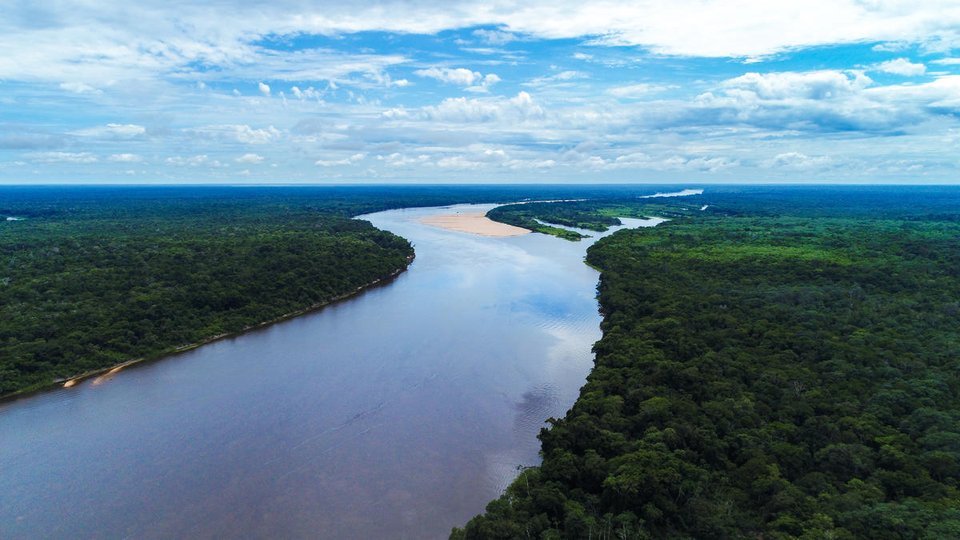 Aerial view of a free-flowing blue river snaking through the green Bolivian Amazon