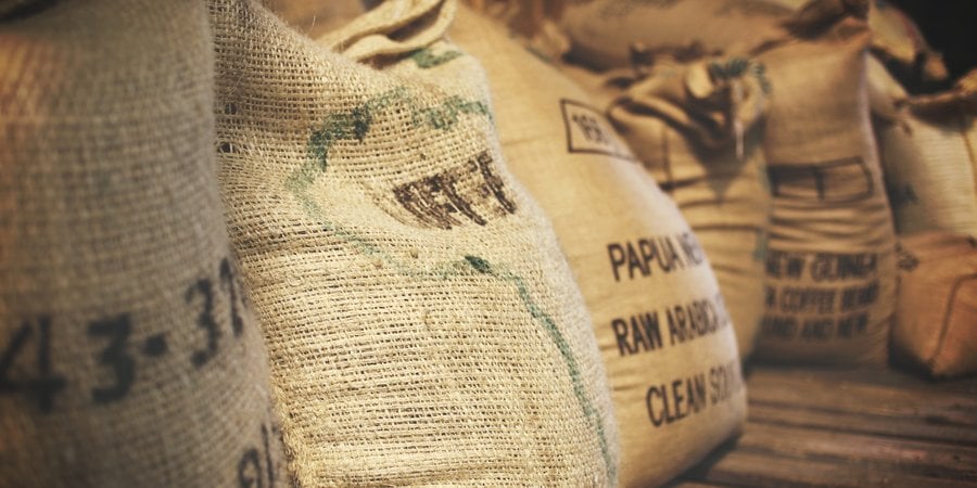 Burlap sacks of coffee against a wooden-planked floor.