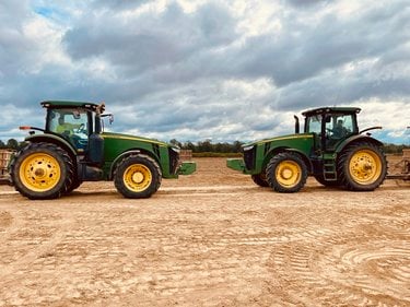 Two tractors face each other in a field