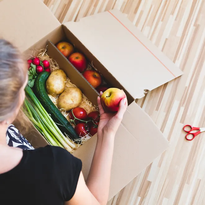 Woman looking into box of vegetables