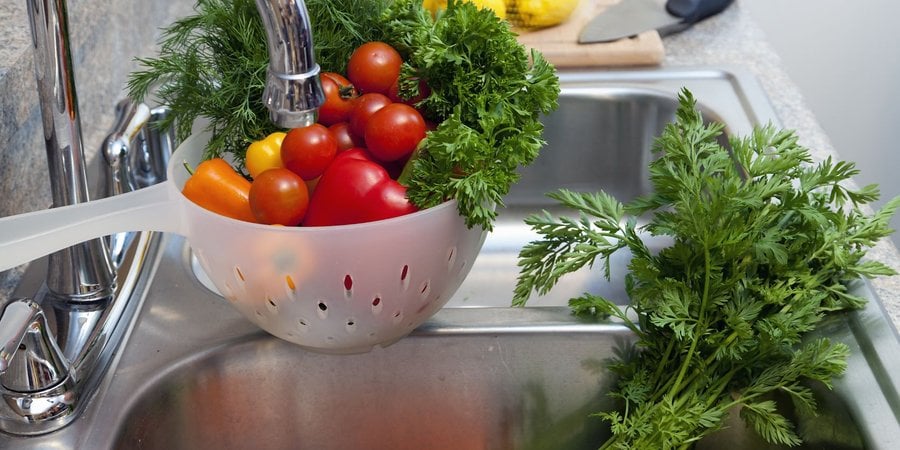 Colorful vegetables in a metal kitchen sink.
