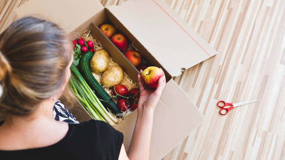 Woman looking into box of vegetables