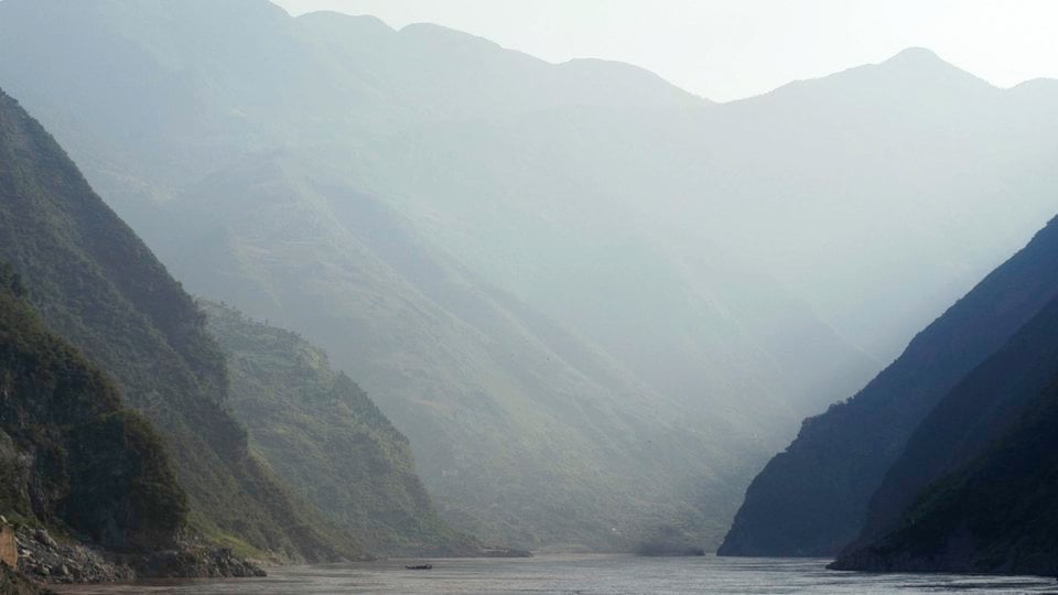 A valley between shadowy mountains with a waterway at the center.